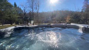 a hot tub in a yard with the sun shining at Cozy Chalet by lake & Nature in Saint-Raymond