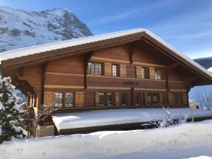 ein großes Holzhaus mit Schnee auf dem Boden in der Unterkunft Excellent flat with a fantastic view of the Eiger! in Grindelwald