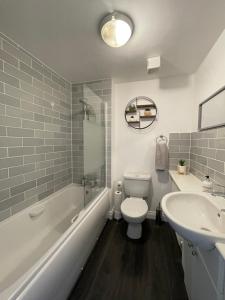 a bathroom with a toilet and a tub and a sink at The Shires in Nuneaton