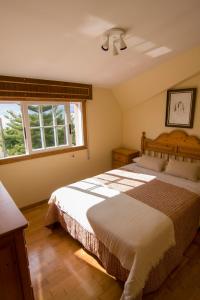 Un dormitorio con una cama grande y dos ventanas. en Playa de Cesantes, en Pontevedra
