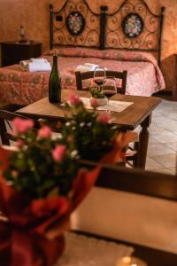 a table with two glasses of wine and flowers on it at Agriturismo Stovali Da Lustrinu in Protte