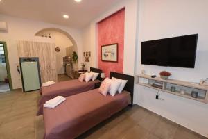 a room with two beds and a flat screen tv at Lolos' house in Rhodes Town
