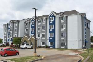 een groot appartementencomplex met een rode auto op een parkeerplaats bij Microtel Inn & Suites By Wyndham Conway in Conway