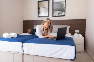 Villa BonnaDea في فاليفو: امرأة مستلقية على سرير مع جهاز كمبيوتر محمول