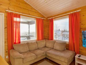 a living room with a couch in front of two windows at Holiday Home Hallan paroni a paritalo by Interhome in Hyrynsalmi