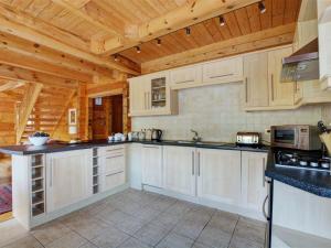 Little PetherickにあるChalet Peroniの白いキャビネットと木製の天井が備わるキッチン
