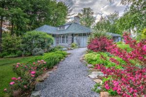 Linville Falls Lodge & Cottages في Linville Falls: حديقة بها زهور وردية ومنزل