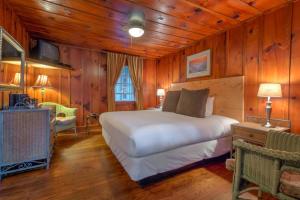Linville Falls Lodge & Cottages في Linville Falls: غرفة نوم بسرير في غرفة بجدران خشبية
