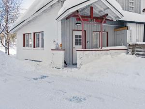 a house with a pile of snow in front of it at Holiday Home Hallantytär b3 paritalo inc- 2 ski ticke by Interhome in Hyrynsalmi