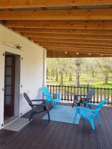 un patio con sillas azules y una mesa en una terraza en Gite du verger, en Mifaget