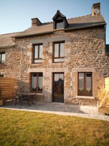 a stone house with picnic tables in front of it at Gite de charme Les Buissonnets in Plesder