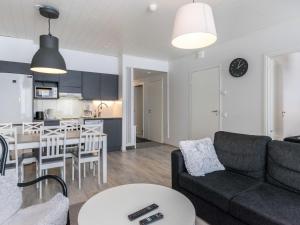 ein Wohnzimmer und eine Küche mit einer Couch und einem Tisch in der Unterkunft Holiday Home Skivillas paljakka 8- - 3mh by Interhome in Kotila