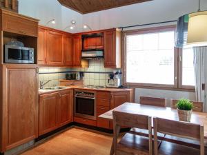 eine Küche mit Holzschränken, einem Tisch und einem Fenster in der Unterkunft Holiday Home Tahkon klubitie 2 a by Interhome in Tahkovuori