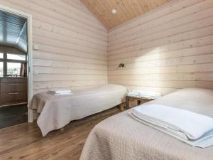 two beds in a room with wooden walls at Holiday Home Hallan karhu c- paritalo by Interhome in Hyrynsalmi +8 photos