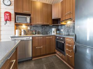 eine Küche mit Holzschränken und einem Kühlschrank aus Edelstahl in der Unterkunft Holiday Home Hallan karhu c- paritalo by Interhome in Hyrynsalmi