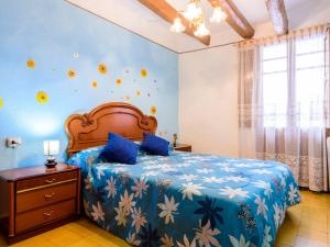 a bedroom with a bed with a blue bedspread with flowers at Holiday Home Hostalas by Interhome in Rosell