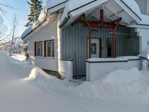 dom pokryty śniegiem z kupą śniegu wokół niego w obiekcie Holiday Home Hallantytär a1 paritalo by Interhome w mieście Hyrynsalmi