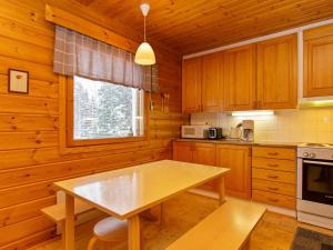 eine Küche mit Holzschränken und einem Tisch im Zimmer in der Unterkunft Holiday Home Paljakan pirtit a3 by Interhome in Kotila