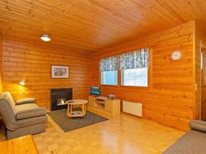 a living room with wooden walls and a fireplace at Holiday Home Paljakan pirtit a3 by Interhome in Kotila