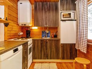 a kitchen with wooden cabinets and a white refrigerator at Holiday Home Lohiukko by Interhome in Kotila
