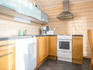 a kitchen with white appliances and wooden walls at Holiday Home Rinteenkotka cottage by Interhome in Hyrynsalmi