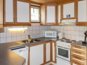 een keuken met witte apparaten en houten kasten bij Holiday Home Miilumaja a1 by Interhome in Kotila