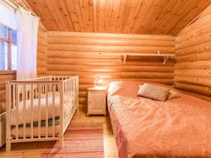ein Schlafzimmer mit einem Kinderbett in einer Blockhütte in der Unterkunft Holiday Home Kultapaljakka 4 by Interhome in Kotila