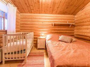 a bedroom with a crib in a log cabin at Holiday Home Kultapaljakka 4 by Interhome in Kotila