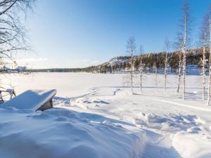 a snow covered field with trees and a bench at Holiday Home Hallantytär b4 paritalo by Interhome in Hyrynsalmi