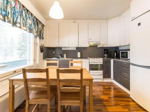a kitchen with white cabinets and a wooden table and chairs at Holiday Home Kotipaljakka a1 by Interhome in Kotila