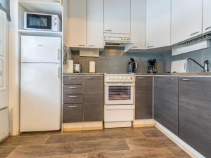 a kitchen with a white refrigerator and wooden cabinets at Holiday Home Kotipaljakka a2 by Interhome in Kotila