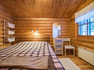 a log cabin bedroom with a bed and a window at Holiday Home Kultapaljakka 3 by Interhome in Kotila