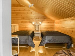 two beds in a room with wooden walls at Holiday Home Miilumaja a2 by Interhome in Kotila