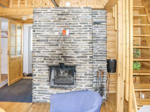 a stone fireplace in a living room with a blue chair at Holiday Home Miilumaja a2 by Interhome in Kotila