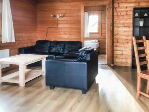 a living room with a black leather couch and a table at Holiday Home De Brenkberg in Schinveld