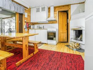 Holiday Home Ahven by Interhome في Hiukkajoki: مطبخ مع طاولة خشبية وسجادة حمراء
