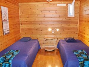 two beds in a room with wooden walls at Holiday Home Miilumaja b1 by Interhome in Kotila