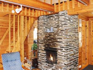 a stone fireplace in a room with a wooden ceiling at Holiday Home Miilumaja b1 by Interhome in Kotila