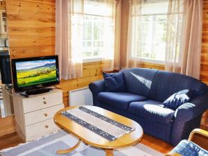 a living room with a blue couch and a tv at Holiday Home Miilumaja b1 by Interhome in Kotila