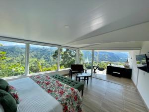 1 dormitorio con cama, sofá y ventanas en Hotel El Mirador del Cocora, en Salento