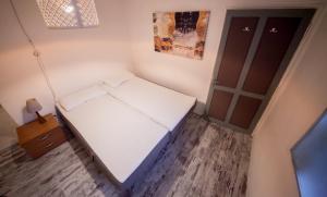 a small bedroom with a white bed and a wooden floor at Maison Ville d'Aoste in Aosta