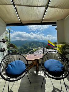 - deux chaises avec des oreillers bleus assises sur un balcon dans l'établissement Hotel El Mirador del Cocora, à Salento