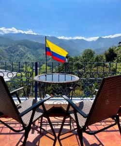 einen Tisch und Stühle auf einem Balkon mit Flagge in der Unterkunft Hotel El Mirador del Cocora in Salento