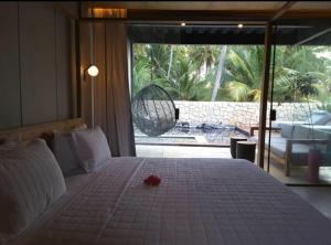 a white bed with a red flower on top of it at Pedras Do Patacho Hotel Boutique Experience in Pôrto de Pedras
