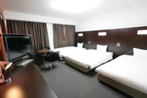 a hotel room with two beds and a flat screen tv at Green Rich Hotel Suizenji in Kumamoto