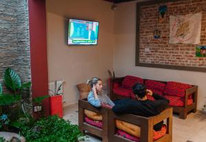 a man and woman sitting in a living room watching a tv at Hotel Italia in Villa Carlos Paz