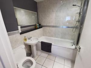 a bathroom with a toilet and a sink and a shower at Large modern GF 1-bed apartment Sleeps 2 in London