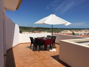 Prestige for Home - Apt Alagoa Praia Altura في ألتورا: طاولة وكراسي مع مظلة على شرفة