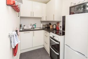 a kitchen with white cabinets and a refrigerator at Rona@Knock View Apartments, Sleat, Isle of Skye in Teangue