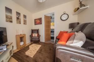 a living room with a couch and a clock on the wall at Rona@Knock View Apartments, Sleat, Isle of Skye in Teangue